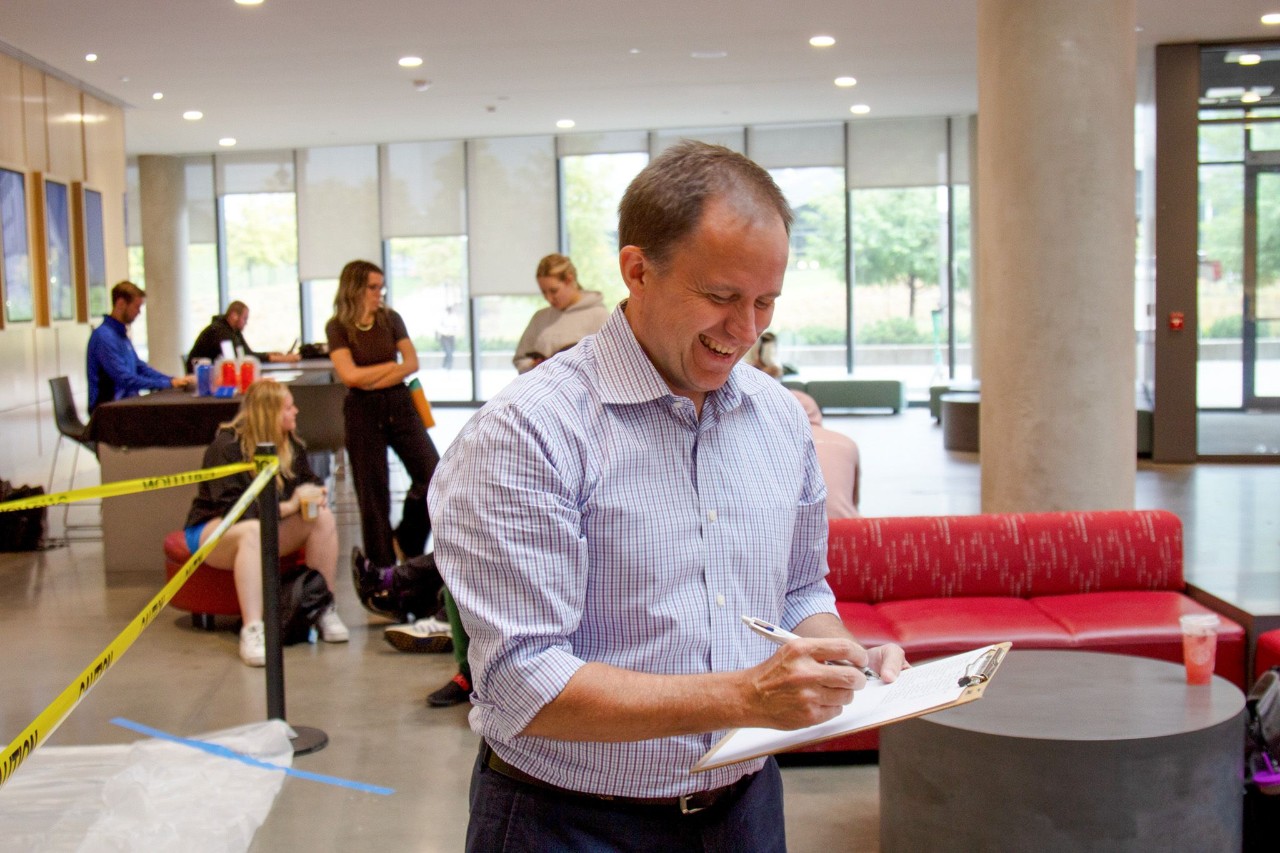 Craig Froehle writes on a clipboard in the Lindner Hall atrium.