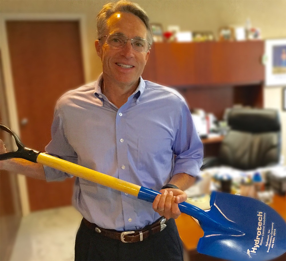 Rex of Hydrotech holds a Hydrotech-branded shovel in an office