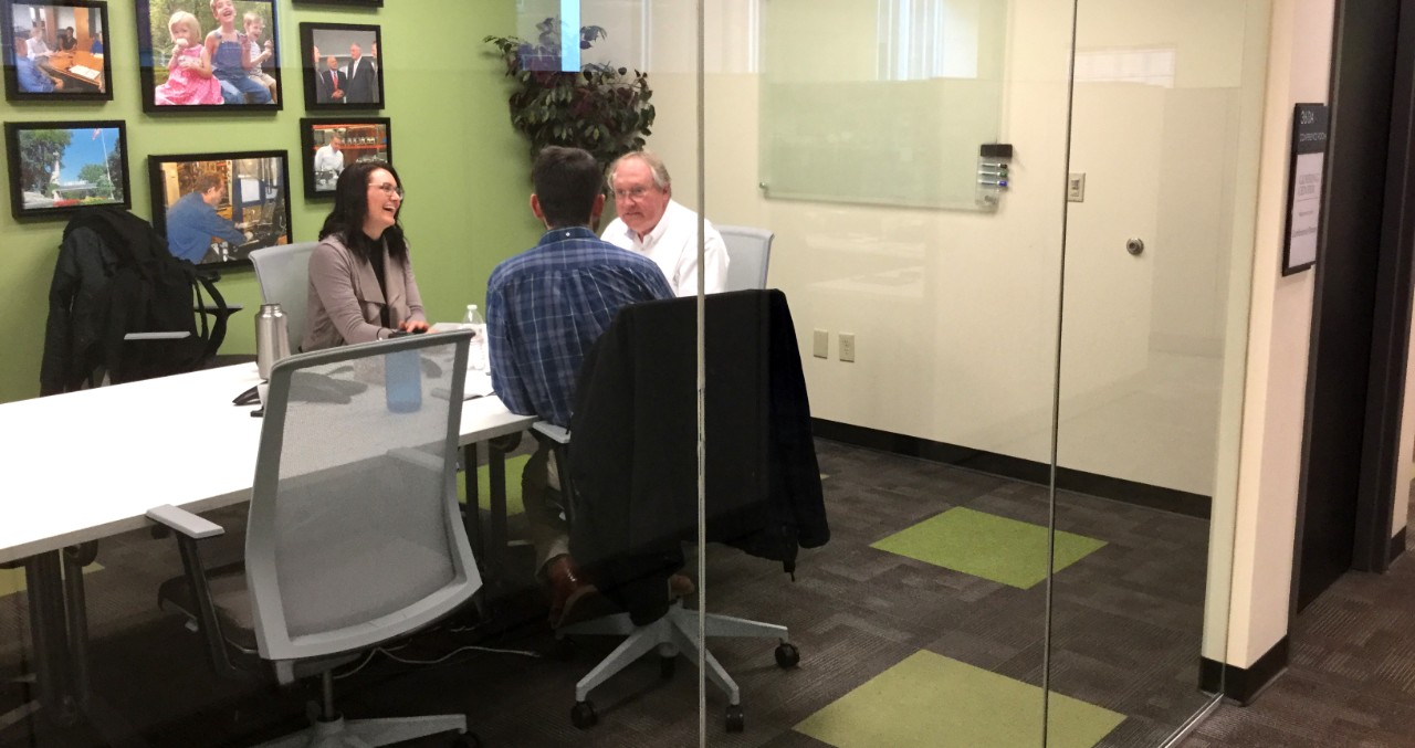 Two business members meeting with Goering Center director in conference room.