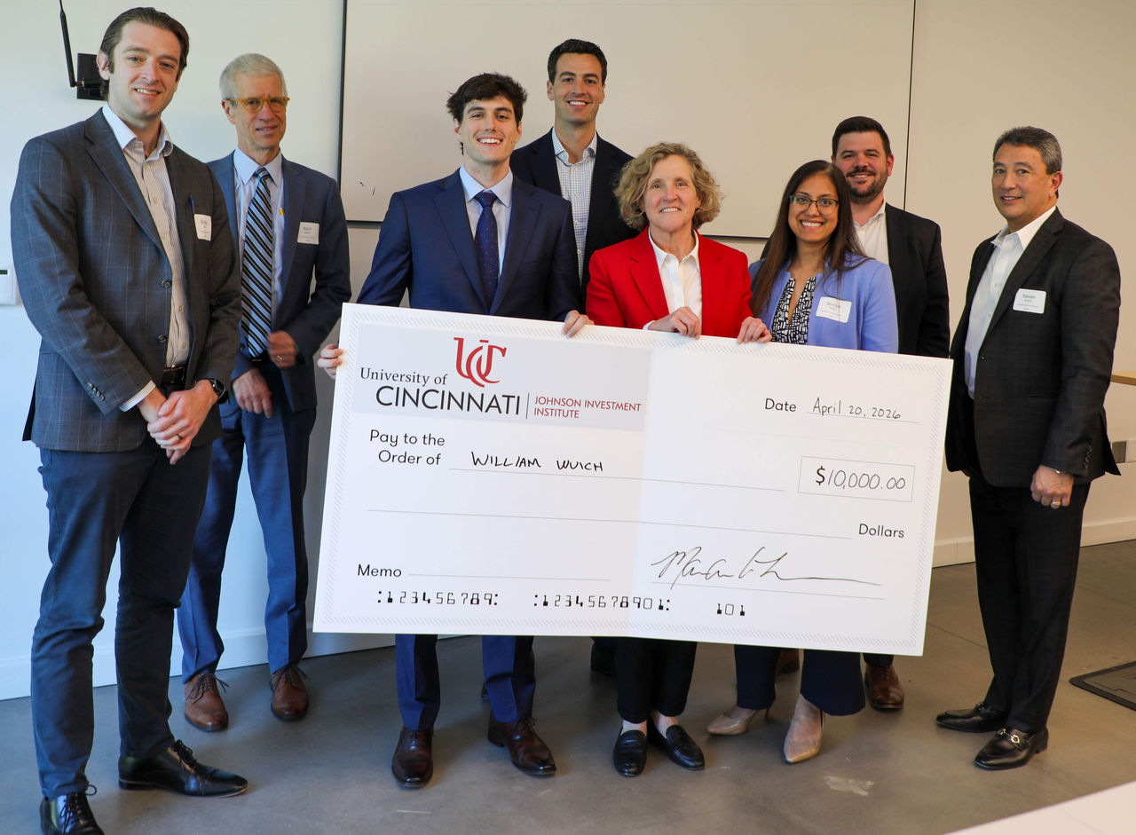 Men and women in professional dress and hold a giant cardboard check.