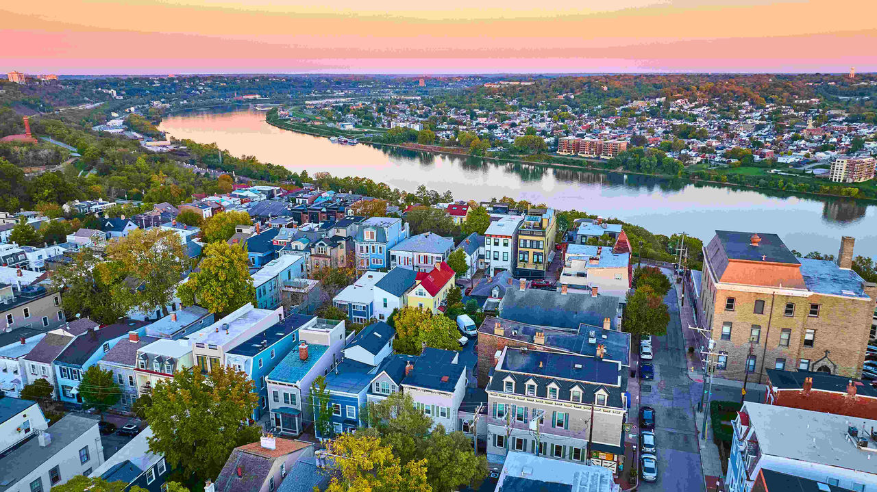 Aerial view of Cincinnati at sunset highlights the harmonious blend of historic and modern architecture along the winding river. Experience the charm and tranquility of this picturesque Ohio town.