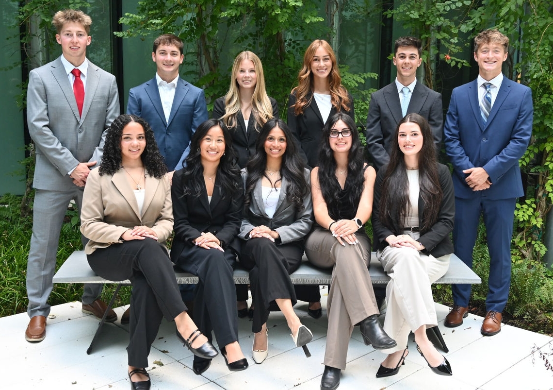 Students from UCREA Exec Board gatherined together dressed in business professional attire to take a group photo