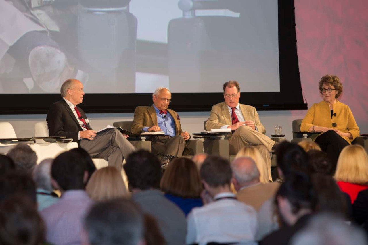 Three men and a woman speak on a panel.