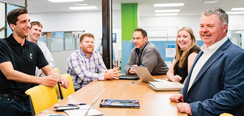 Scott Anderson, far right, converses with five other people around a table in Enerfab's offices