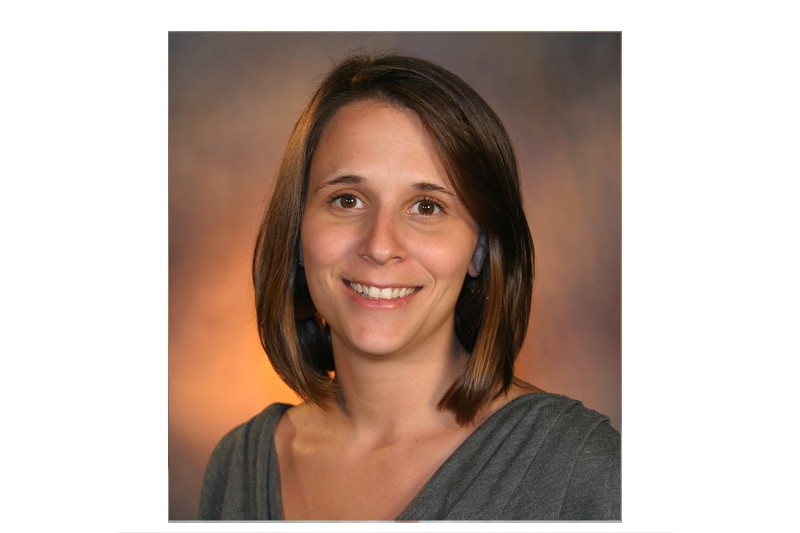 A woman smiles wearing a green shirt.