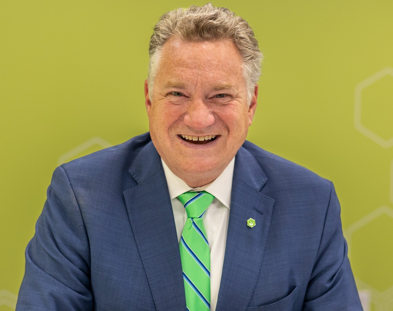 A man wears a dark blue suit and bright green tie.