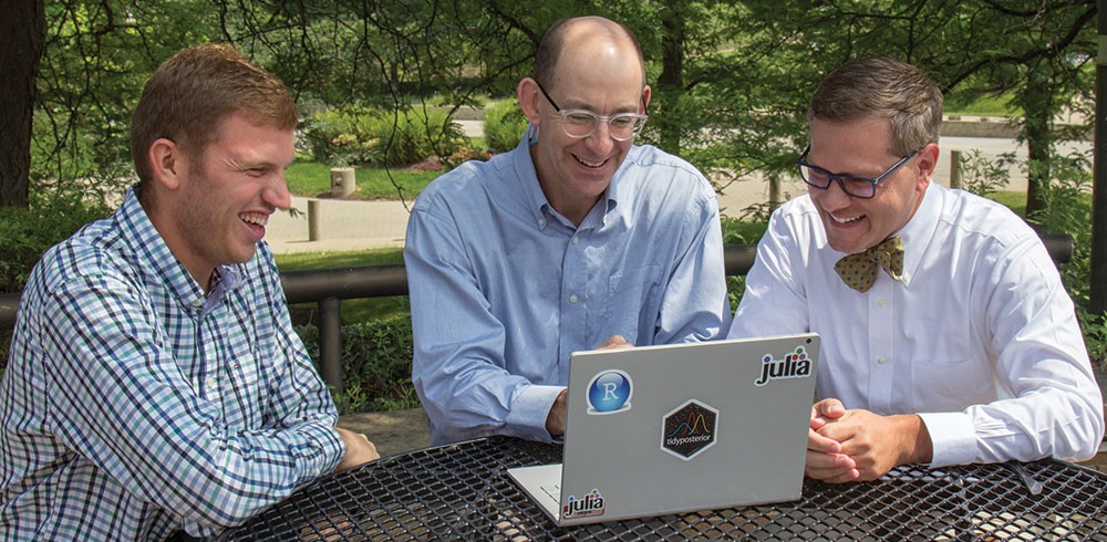 Left to right: Beau Sauley, Jeffrey Mills, and Jeffrey Strawn, seated at an outdoor table around a laptop