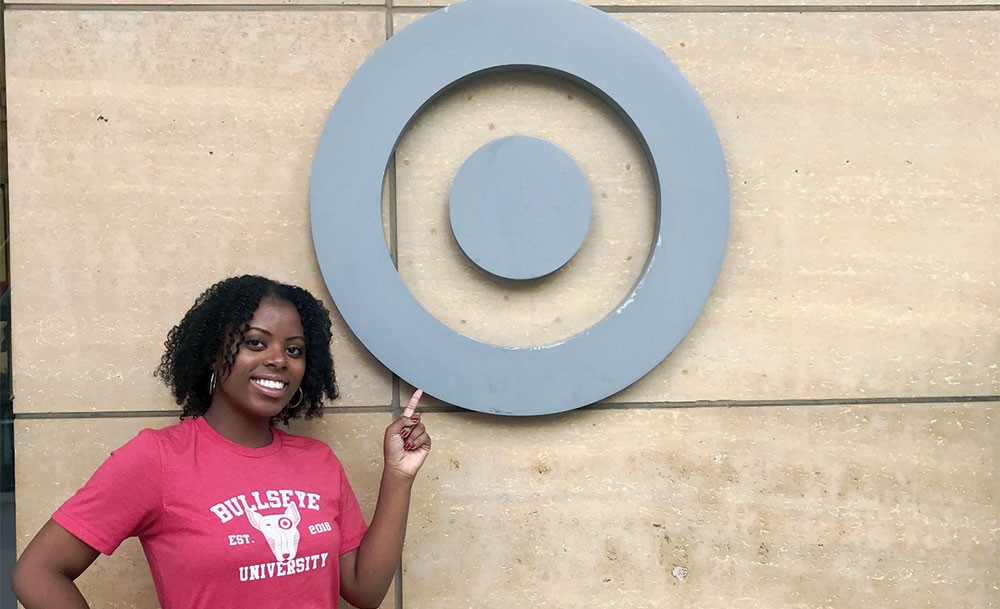 Angela Brown wearing a "Bullseye University" t-shirt pointing to a Target logo