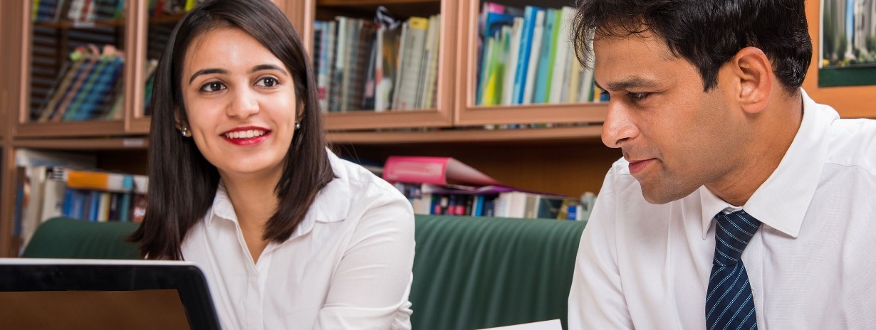 A businesswoman and businessman reviewing documents at an office table