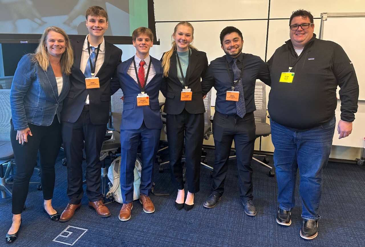 Lindner student in professional dress with Deloitte employees during the case competition. 