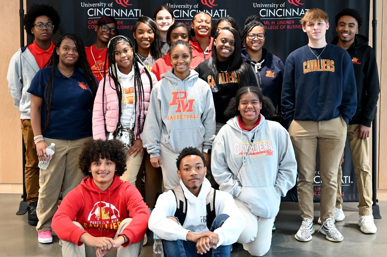 A group of Purcell Marian high school students pose in front of a Lindner banner in the Lindner Hall atrium.