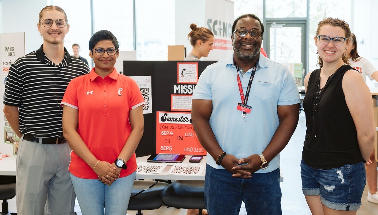 Four people stand and smile during the student organizations fair.